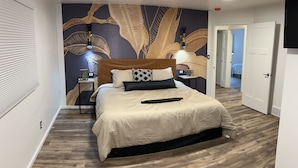 Ein modernes Schlafzimmer mit einem großen Bett, einer Wandverkleidung und einem Holzboden.