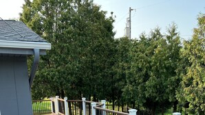 Eine Holzterrasse mit weißen Geländern und ein graues Gebäude im Vordergrund.