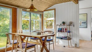 A dining area with a wooden table and chairs, a pendant light, and a view of the outdoors.