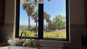 A kitchen with a large window, a sink, and a ceiling fan. - Ocean Breezes VRBO (Fallbrook)