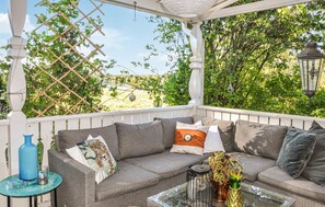 Un espace extérieur aménagé, abrité et doté d’un canapé confortable, d’une petite table et d’objets décoratifs.