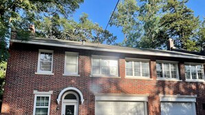 A two-story brick house with a garage, a front door, and a small porch area.