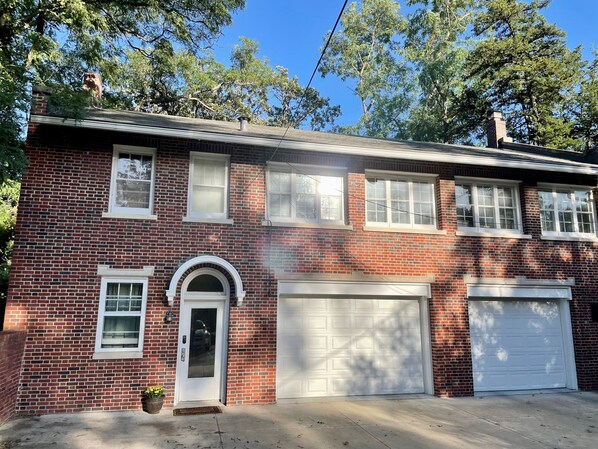 A two-story brick house with a garage, a front door, and a small porch area. - South of Grand Carriage House- minutes from downtown Des Moines (DES MOINES)