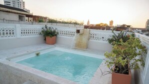 A rooftop swimming pool with a water feature, surrounded by a white decorative wall and potted plants. - old City 5br Piscina Rooftop AC hot Water (Cartagena de Indias)