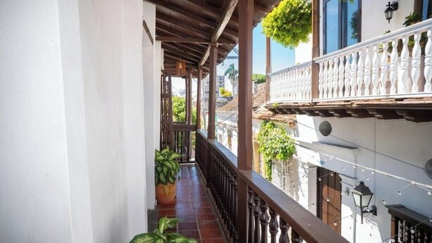 A covered balcony with a tiled floor, potted plants, and a railing. - old City 5br Piscina Rooftop AC hot Water (Cartagena de Indias)