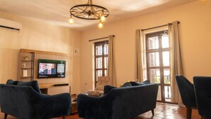 A living room with a television, two sofas, a patterned armchair, and a chandelier. - old City 5br Piscina Rooftop AC hot Water (Cartagena de Indias)