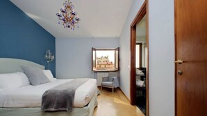 Ein Schlafzimmer mit Bett, Sessel, Fenster und Tür.