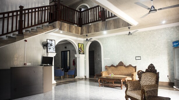 Amplia sala de estar con techo alto, una escalera y un área de descanso con sofá y sillones.