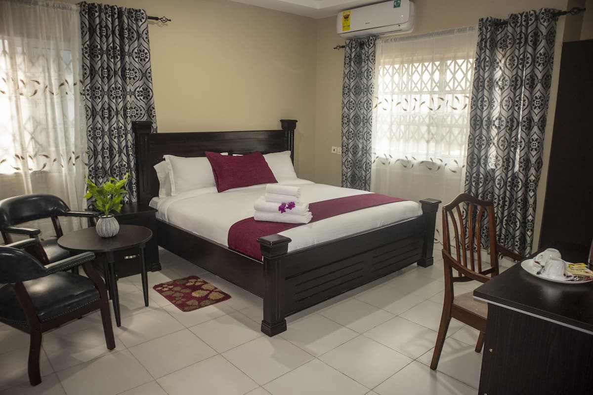 Una habitación de hotel ordenada con cama, una mesita, una silla y un escritorio.