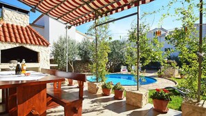 An outdoor patio with a pool, stone walls, and potted plants. - Stunning apartment in Tribunj (Tribunj)