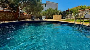 A clear swimming pool with a stone wall and a metal ladder on the right. - Stunning apartment in Tribunj (Tribunj)