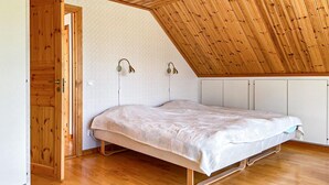 A bedroom with a sloped ceiling, a bed, and two wall-mounted lamps.