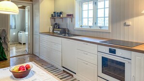 A kitchen with white cabinets, a built-in oven, a window above the sink, and a bowl of fruit on the floor. - 3 bedroom nice home in Kvam (Kvam)