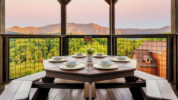 Un coin repas avec une table dressée pour six personnes, offrant une vue sur un paysage montagneux.
