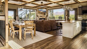 Une cuisine spacieuse avec un grand îlot central, un plancher en bois et une vue sur les montagnes grâce à de grandes fenêtres.