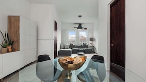 Een modern interieur met een glazen eettafel, zwarte stoelen, een bank en een houten kast.
