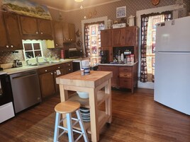 Una cocina con armarios de madera, una isla de madera con taburetes, un refrigerador y varios electrodomésticos.