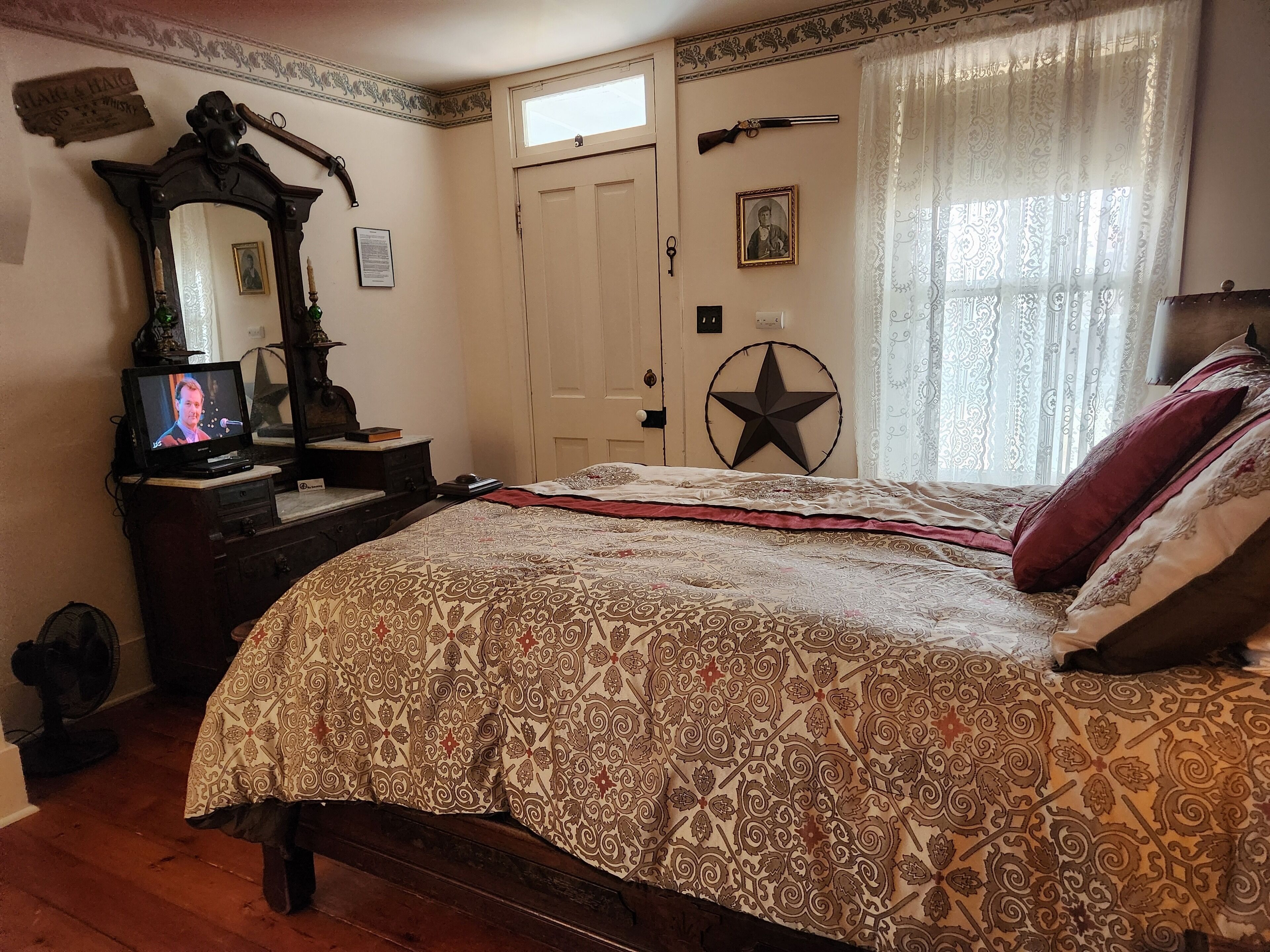 Ein Schlafzimmer mit einem großen Bett, einem Schminktisch mit Spiegel, einem Fernseher und einer Stern-Dekoration an der Wand.