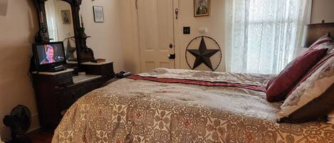Ein Schlafzimmer mit einem großen Bett, einem Schminktisch mit Spiegel, einem Fernseher und einer Stern-Dekoration an der Wand.