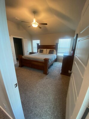 A bedroom with a bed, a ceiling fan, and a window with blinds.