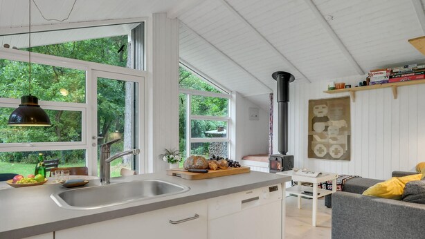 Una cucina moderna con un'ampia finestra, piano cottura integrato e angolo pranzo con divano grigio.