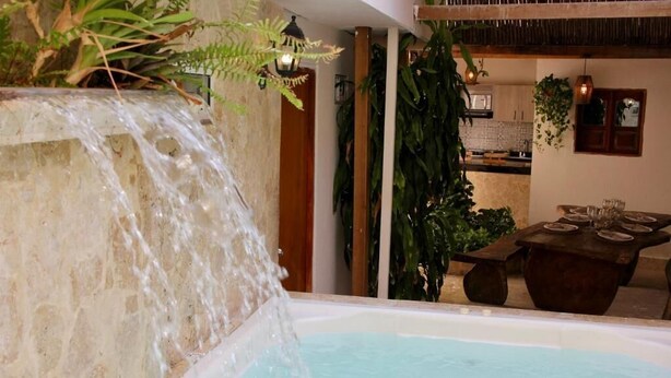 Ein Wellnessbereich mit Wasserspiel, Esstisch und üppiger Bepflanzung.