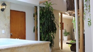 Ein Wellnessbereich mit einer Steinbadewanne, einer Holztür und einer großen Topfpflanze.