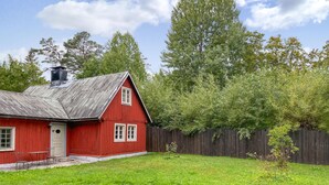 A red wooden house with a metal roof, a wooden fence, and a grassy yard. - 3 bedroom cozy home in Lärbro (Lärbro)