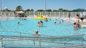 Piscina pública com várias pistas de natação, posto de salva-vidas e área cercada.