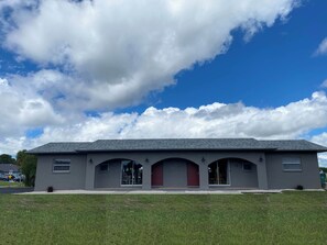 A single-story building with a flat roof, a red door, and multiple windows.