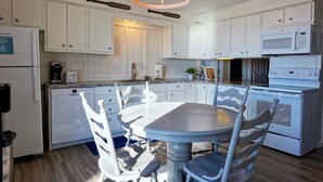 Uma cozinha com armários brancos, uma ilha central com assentos, micro-ondas e máquina de lavar louça.