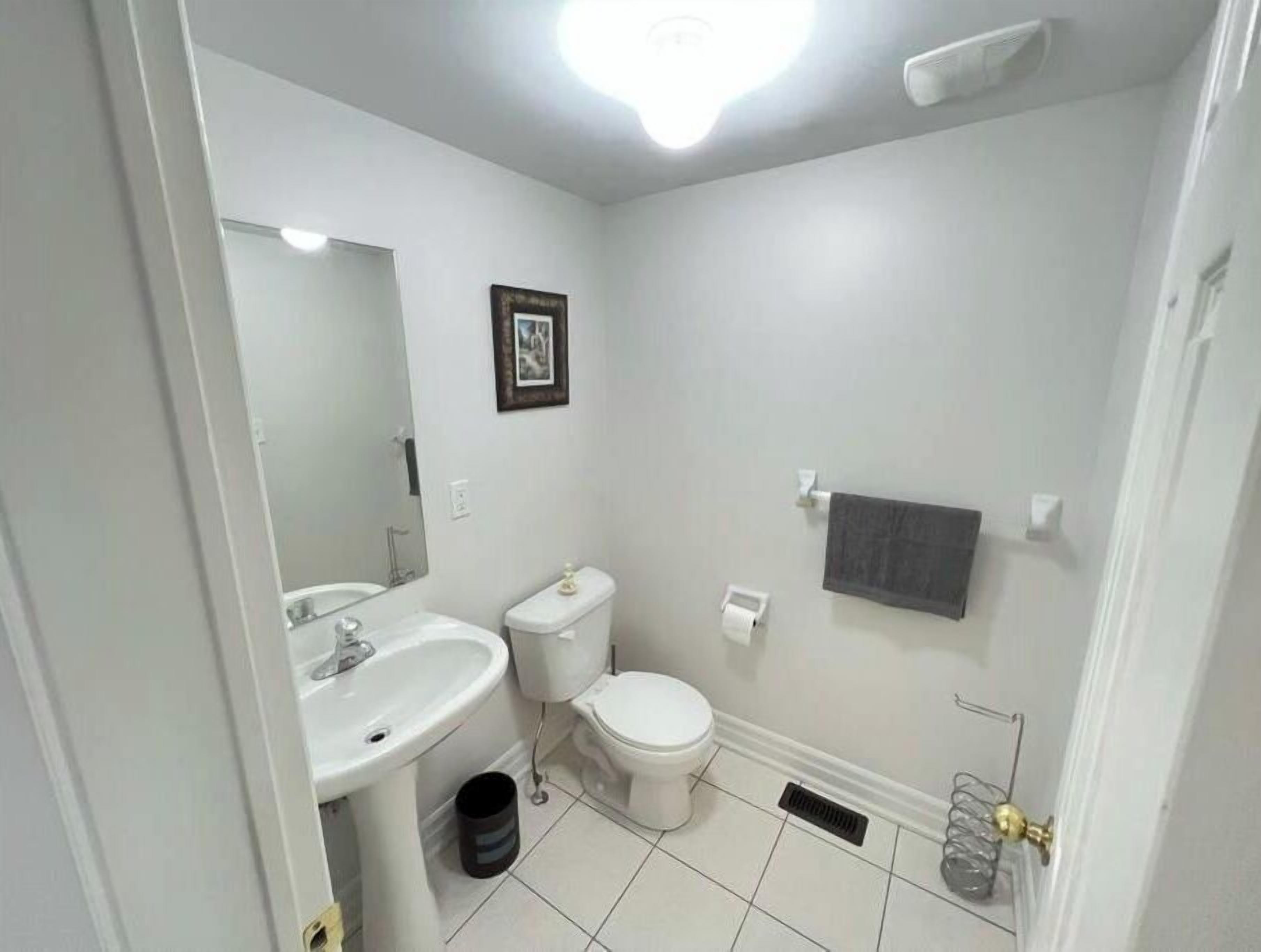 Un baño pequeño y limpio con sanitarios blancos, un espejo, un inodoro y un lavabo.