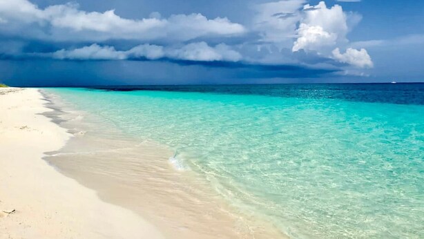 A beach with clear turquoise water and a sandy shore under a partly cloudy sky. - Beautiful Condo on the Beach in Freeport! (Freeport)