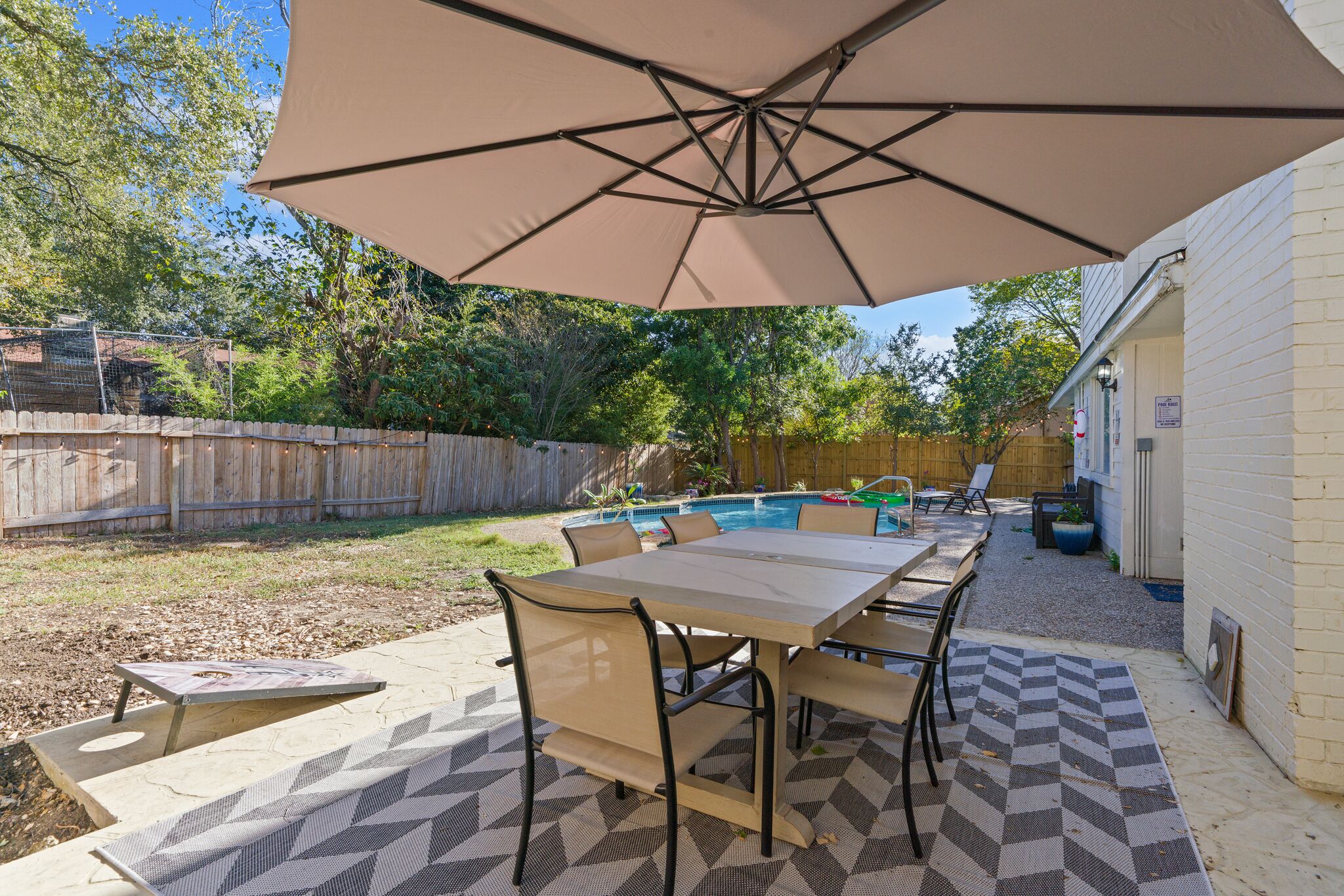 Une terrasse avec une table et des chaises, une piscine et une clôture en bois.