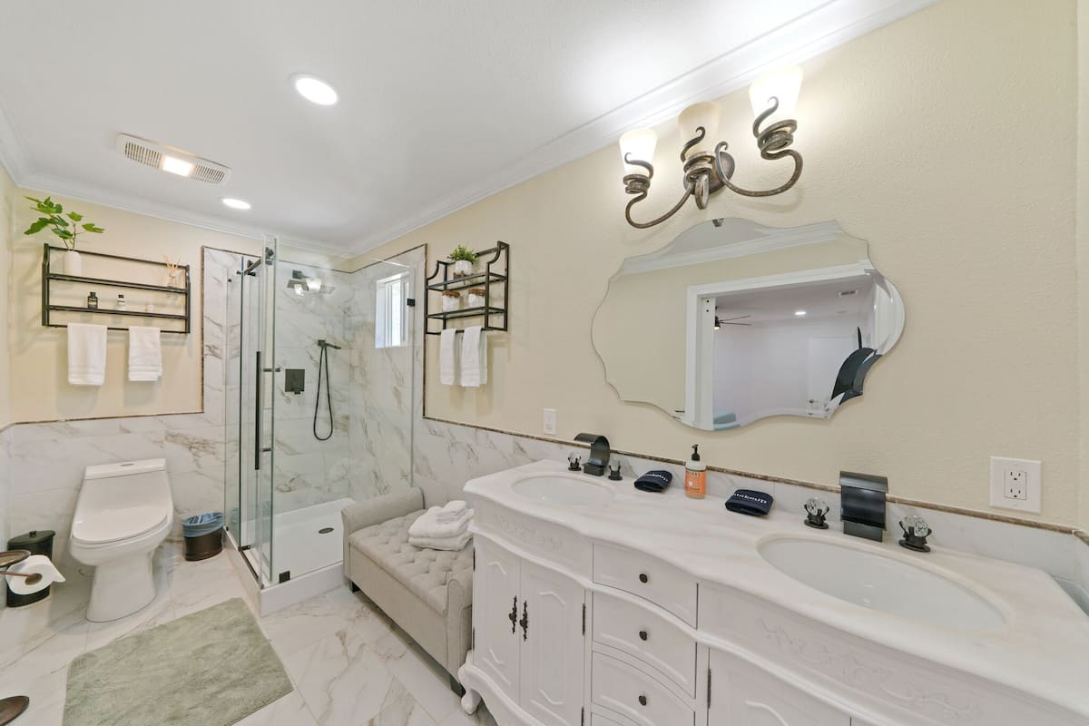 A modern bathroom with a glass-enclosed shower, a large white sink, and a vanity with drawers.