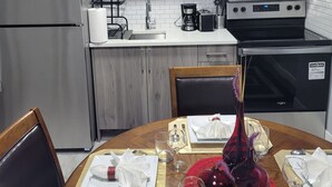 Uma cozinha moderna com armários cinza, geladeira de aço inoxidável, micro-ondas e forno.