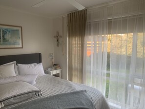 Cozy retreat with a large bed, bedside table, and a window with sheer curtains.