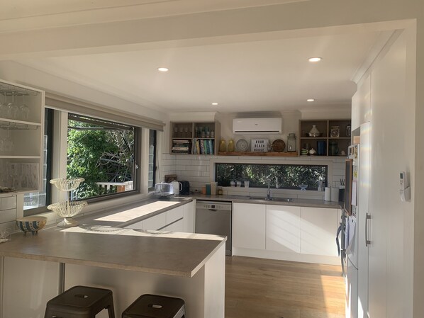 Enjoy a serene view of the lush garden from this kitchen, which features a large island, dishwasher, and stainless steel sink.