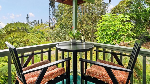 A covered outdoor seating area with a table and chairs, surrounded by lush greenery and trees. - Peaceful Mountain Retreat- Jungle Mountain Vibes (Holualoa)