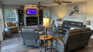 A living room with a fireplace, leather sofas, a coffee table, and a television. - Lake Hamilton, BoatHouse, Hot Tub, 
Barge Rental, Sleeps 10, H.S. National Park (Hot Springs)
