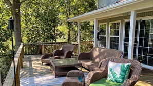A covered outdoor deck with wicker furniture, including a sofa and chairs, and a table. - Lake Hamilton, BoatHouse, Hot Tub, 
Barge Rental, Sleeps 10, H.S. National Park (Hot Springs)