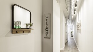 A hallway with a 'WELCOME' sign, a mirror, and a shelf with decorative items. - Beautiful 1BR in Midtown and the Medical District  (Memphis)
