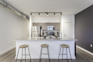 A modern kitchen with a central island, stainless steel appliances, and bar stools.