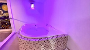 A circular jacuzzi with mosaic tile flooring, a small wall-mounted light, and a painting on the adjacent wall. - suite old city 11br jacuzzi Ac Hot water (Cartagena de Indias)