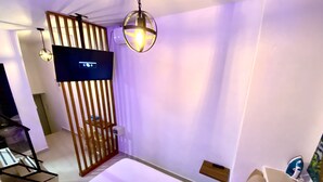 A hotel room with a bed, a TV, a wooden partition, and a hanging light fixture. - suite old city 11br jacuzzi Ac Hot water (Cartagena de Indias)