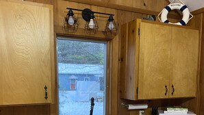 Una cocina con armarios de madera, una ventana, un lavamanos, un microondas y un cartel que dice 'WELCOME'.