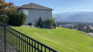 Una casa con tetto spiovente, un piccolo patio e vista sulla valle e sulle montagne.