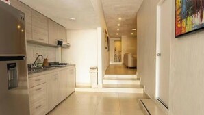 Una cocina moderna con armarios de madera clara, electrodomésticos de acero inoxidable y suelo de baldosas.