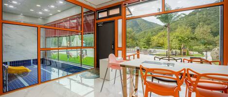 A modern interior with a glass pool, dining area, and mountain views.