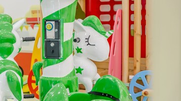 Un carrusel con caballos verdes y blancos, incluyendo un caballo central con un panel de control.